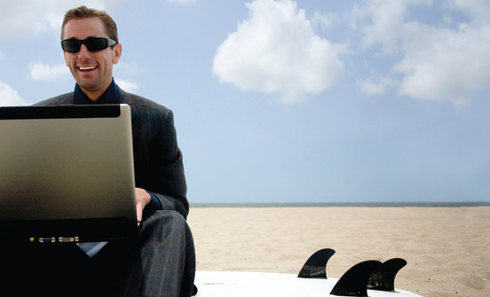 Man in Suit Sitting on Beach with Laptop